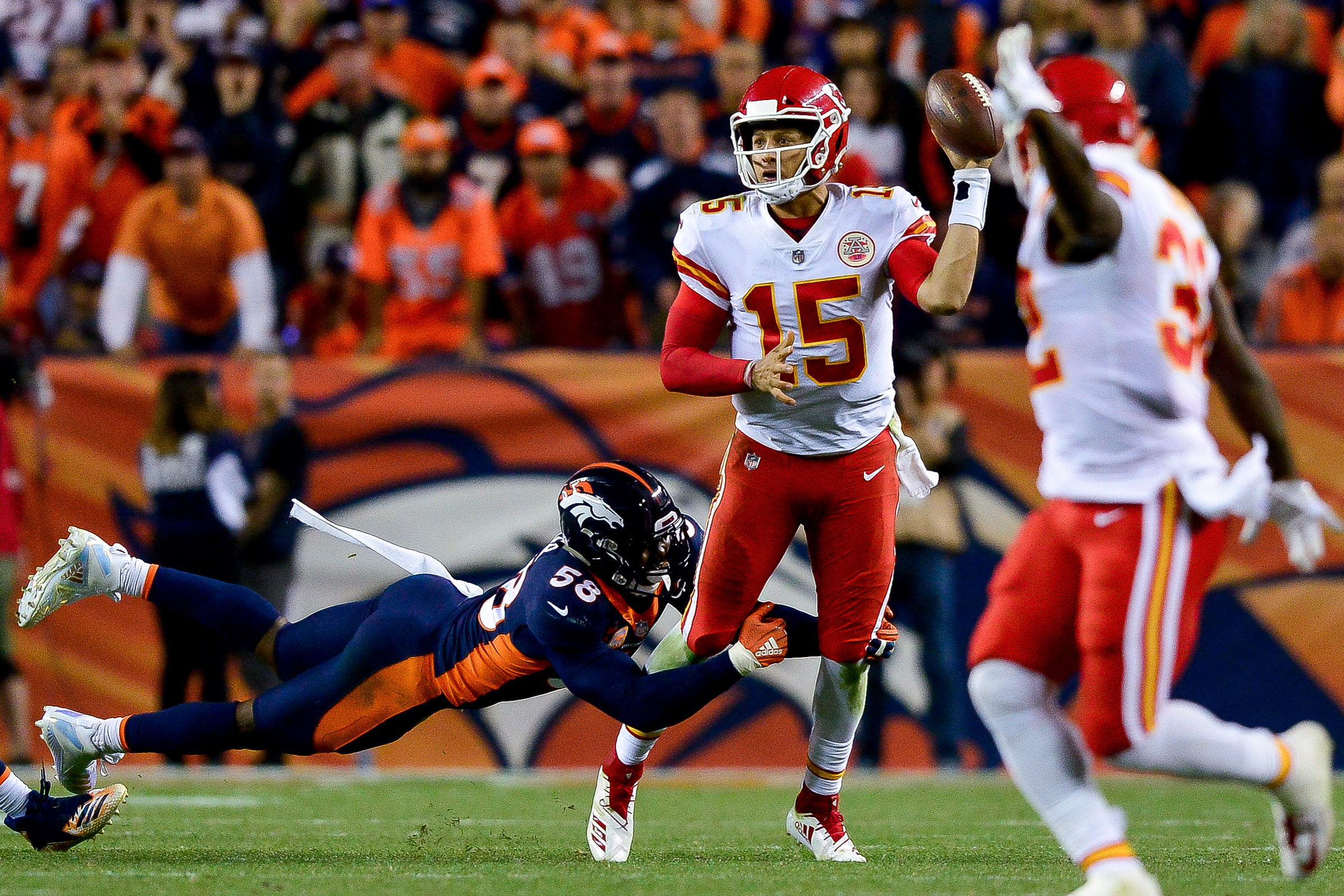 DENVER, CO - OCTOBER 1: Quarterback Patrick Mahomes #15 of the Kansas City Chiefs throws a left-handed pass for a completion while he is hit by linebacker Von Miller #58 of the Denver Broncos in the fourth quarter of a game at Broncos Stadium at Mile High on October 1, 2018 in Denver, Colorado. (Photo by Dustin Bradford/Getty Images)