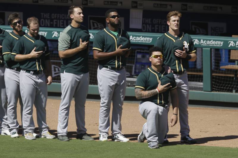 Oakland Athletics catcher Bruce Maxwell takes a knee next to teammate Mark Canha, right, during the national anthem before a baseball game against the Texas Rangers in Arlington, Texas, Sunday, Oct. 1, 2017. (AP Photo/LM Otero)