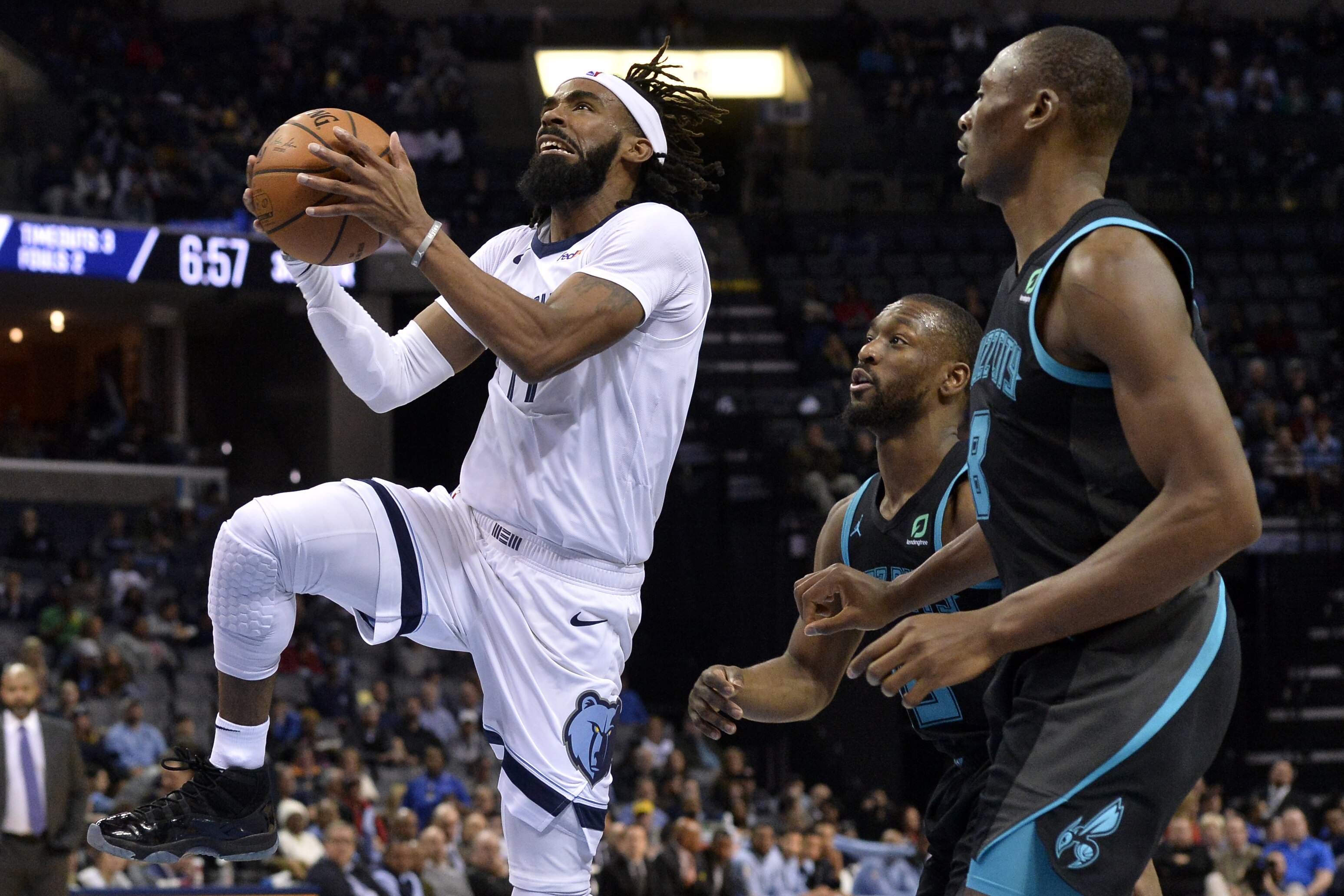 Memphis Grizzlies guard Mike Conley, left, shoots ahead of Charlotte Hornets center Bismack Biyombo, right, and guard Kemba Walker in the second half of an NBA basketball game, Wednesday, Jan. 23, 2019, in Memphis, Tenn. (AP Photo/Brandon Dill)
