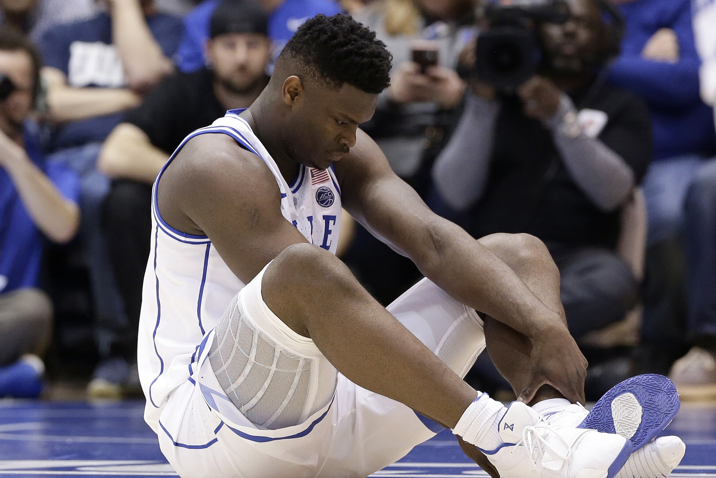 Duke's Zion Williamson sits on the floor following a injury during the first half of an NCAA college basketball game against North Carolina, in Durham, N.C., Wednesday, Feb. 20, 2019. Duke might have to figure out what the Zion Show will look like without its namesake. All because of a freak injury to arguably the most exciting player in college basketball. As his Nike shoe blew out, Williamson sprained his right knee on the first possession of what became top-ranked Duke's 88-72 loss to No. 8 North Carolina.(AP Photo/Gerry Broome)