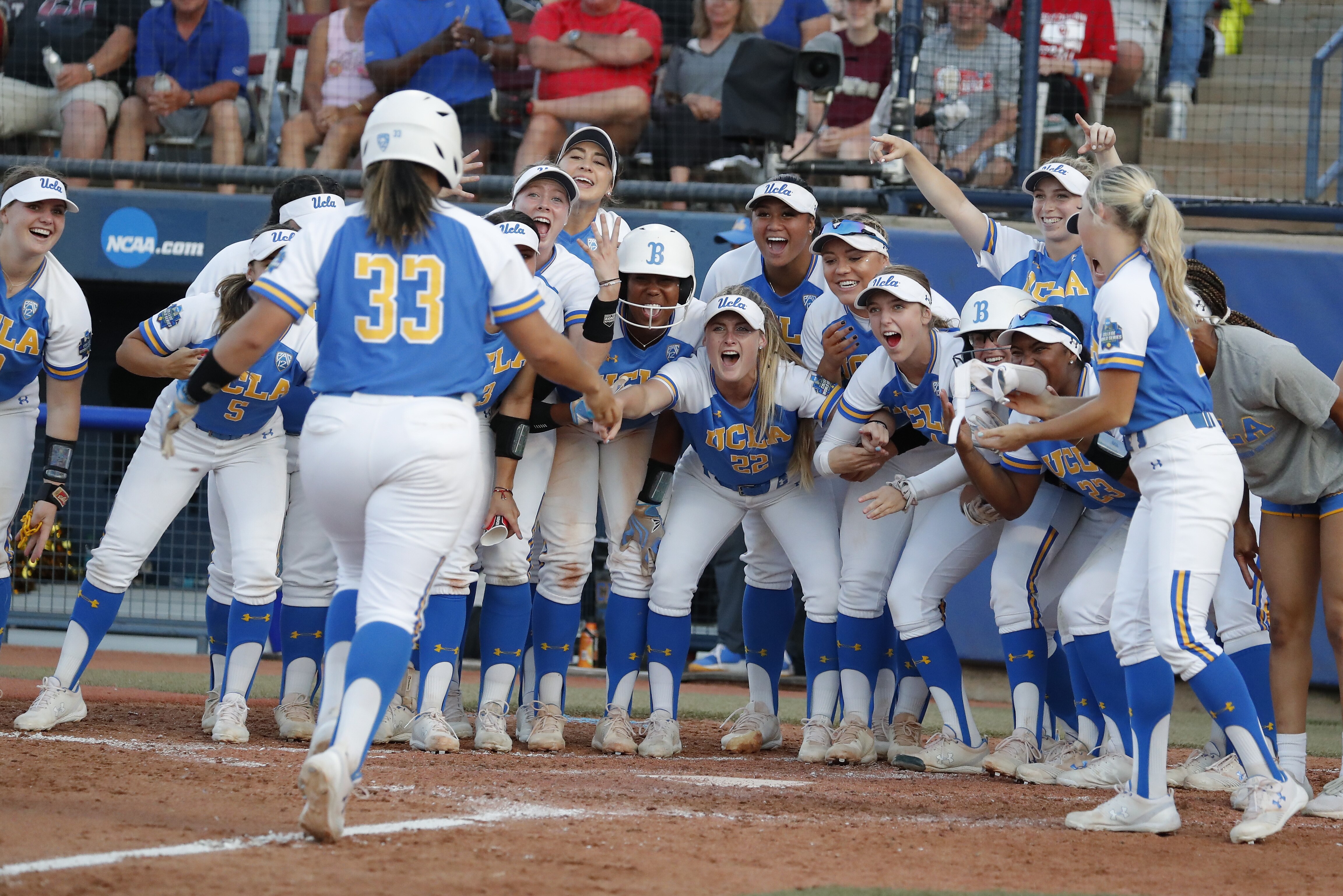 UCLA's Brianna Tautalafua (33) is greeted by teammates after a home run in the sixth inning against Oklahoma during the first game of the best-of-three championship series in the NCAA softball Women's College World Series in Oklahoma City, Monday, June 3, 2019. (AP Photo/Alonzo Adams)