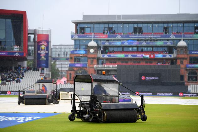 MANCHESTER, ENGLAND - JULY 09: The ground staff work to keep the pitch dry as play is delayed due to rain during the Semi-Final match of the ICC Cricket World Cup 2019 between India and New Zealand at Old Trafford on July 09, 2019 in Manchester, England. (Photo by Clive Mason/Getty Images)