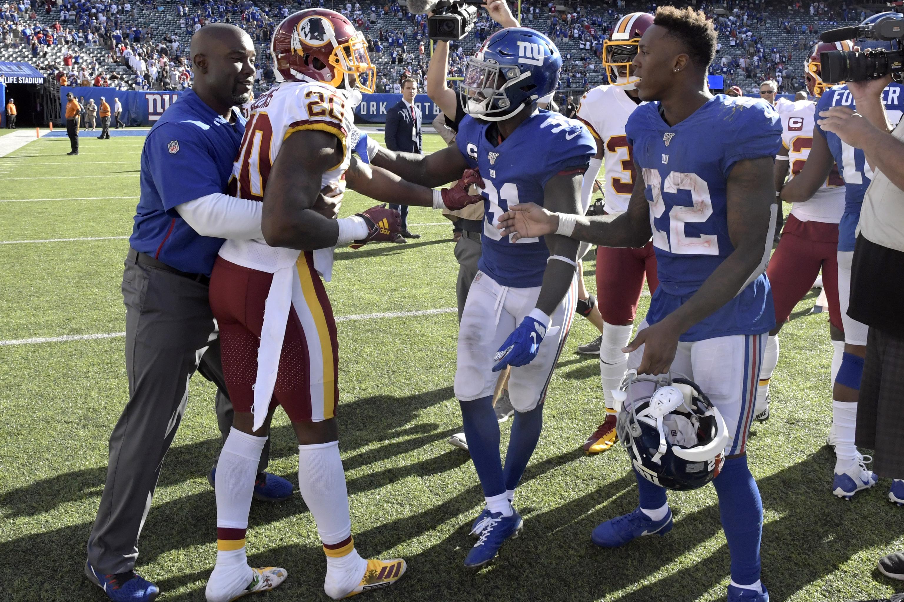 Washington Redskins strong safety Landon Collins (20) and New York Giants  running back Saquon Barkley (26) trade jerseys following an NFL football  game between the New York Giants and the Washington Redskins