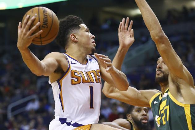 Phoenix Suns guard Devin Booker (1) shoots as Utah Jazz center Rudy Gobert (27) and forward Royce O'Neale (23) defend during the first half of an NBA basketball Wednesday, April 3, 2019, in Phoenix. (AP Photo/Ross D. Franklin)