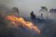 A firefighter sprays water in front of an advancing wildfire Friday, Oct. 11, 2019, in Porter Ranch, Calif. (AP Photo/Marcio Jose Sanchez)