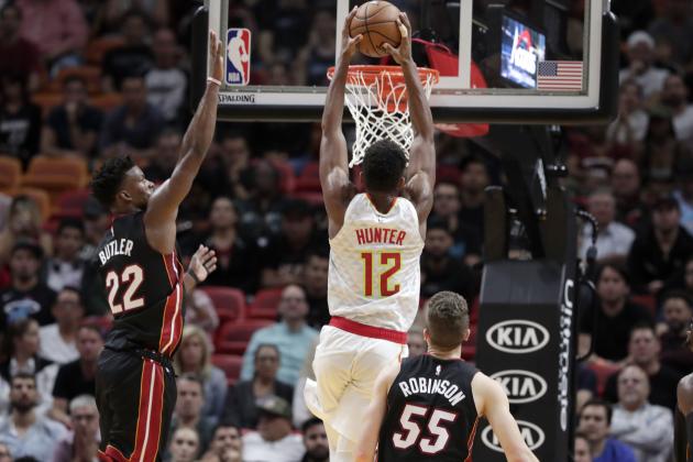 Atlanta Hawks forward De'Andre Hunter (12) dunks over Miami Heat forward Jimmy Butler (22)and forward Duncan Robinson (55) during the second half of an NBA basketball game, Tuesday, Dec. 10, 2019, in Miami. The Heat won 135-121 in overtime. (AP Photo/Lynne Sladky)