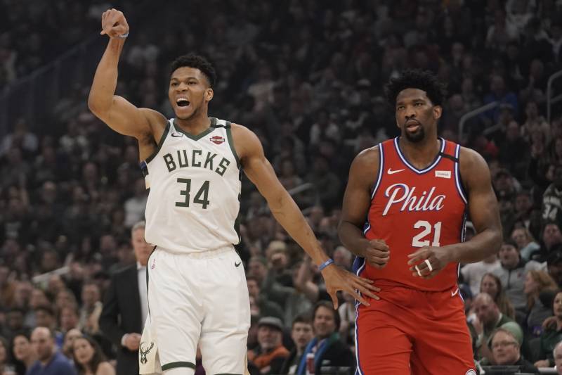 Milwaukee Bucks' Giannis Antetokounmpo reacts to his shot in front of Philadelphia 76ers' Joel Embiid during the first half of an NBA basketball game Saturday, Feb. 22, 2020, in Milwaukee. (AP Photo/Morry Gash)