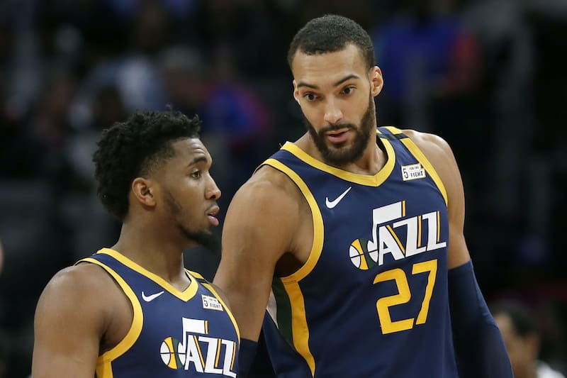 FILE - In this Saturday, March 7, 2020, file photo, Utah Jazz center Rudy Gobert (27) talks with guard Donovan Mitchell, left, during the second half of an NBA basketball game against the Detroit Pistons, in Detroit. Both players have tested positive for the coronavirus. Gobert's test result forced the NBA to suspend the season. (AP Photo/Duane Burleson, File)