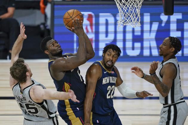 New Orleans Pelicans forward Zion Williamson, center, with help from teammate Derrick Favors (22) takes a shot as he gets past San Antonio Spurs center Jakob Poeltl, left, during the second half of an NBA basketball game, Sunday, Aug. 9, 2020, in Lake Buena Vista, Fla. (AP Photo/Ashley Landis, Pool)