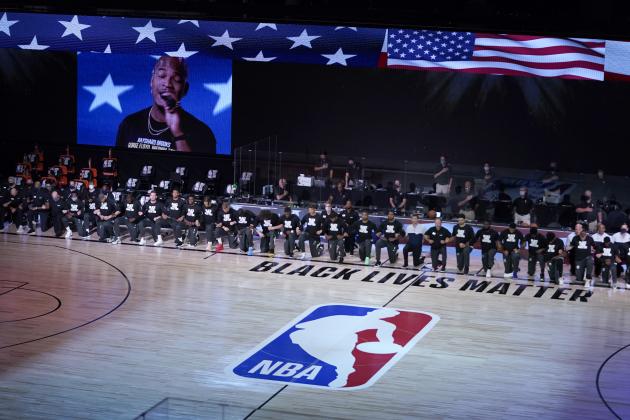 Members of the Milwaukee Bucks and the Boston Celtics kneel around a Black Lives Matter logo during the national anthem before the start of an NBA basketball game Friday, July 31, 2020, in Lake Buena Vista, Fla. (AP Photo/Ashley Landis, Pool)