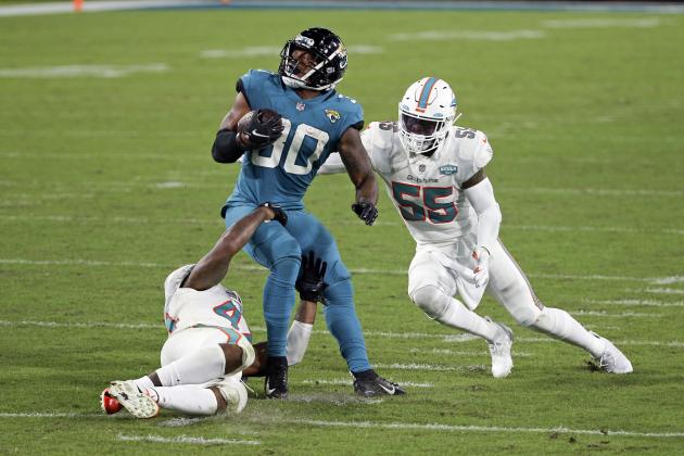 Jacksonville Jaguars running back James Robinson, center, looks for a way to get past Miami Dolphins outside linebacker Elandon Roberts, left, and outside linebacker Jerome Baker (55) during the second half of an NFL football game, Thursday, Sept. 24, 2020, in Jacksonville, Fla. (AP Photo/Stephen B. Morton)
