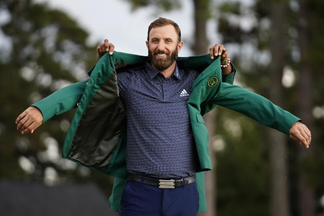 Tiger Woods helps Masters champion Dustin Johnson with his green jacket after his victory at the Masters golf tournament Sunday, Nov. 15, 2020, in Augusta, Ga. (AP Photo/Matt Slocum)