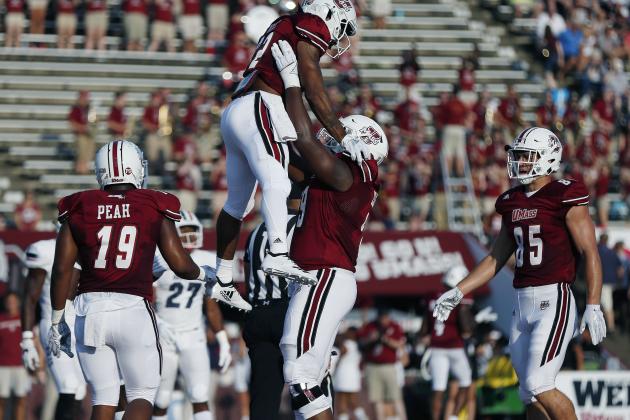 Massachusetts running back Bilal Ally, center top, celebrates his touchdown with offensive lineman Larnel Coleman, center bottom, during the first half of an NCAA college football game against Duquesne in Amherst, Mass., Saturday, Aug. 25, 2018. (AP Photo/Michael Dwyer)
