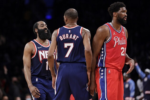 Brooklyn Nets guard James Harden (13) and Kevin Durant (7) react behind Philadelphia 76ers center Joel Embiid (21) during the second half of an NBA basketball game Thursday, Dec. 30, 2021, in New York. 76ers won 110-102. (AP Photo/Adam Hunger)