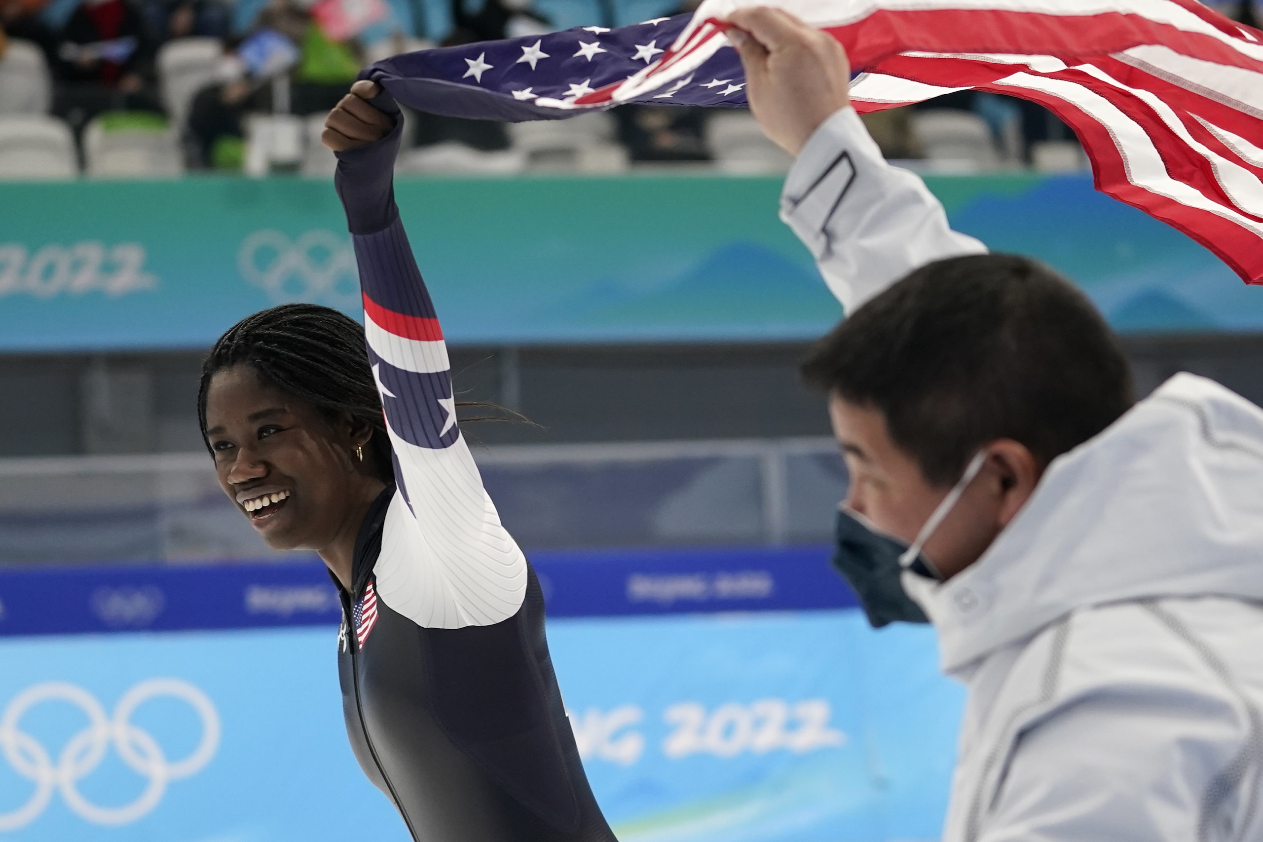 Erin Jackson of the United States holds up an American flag with coach Ryan Shimabukuro after winning the gold medal in the speedskating women's 500-meter race at the 2022 Winter Olympics, Sunday, Feb. 13, 2022, in Beijing. (AP Photo/Ashley Landis)