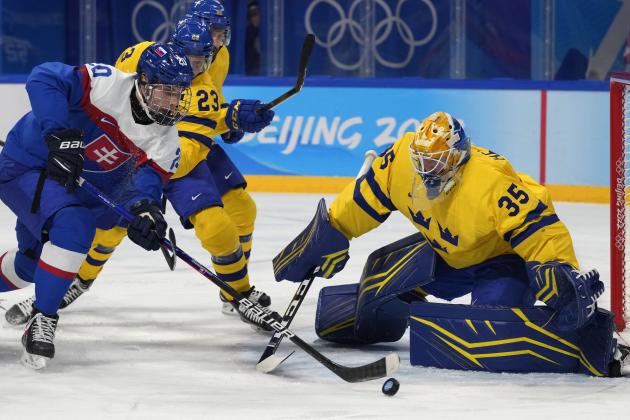 Slovakia's Juraj Slafkovsky (20) goes for the puck in front of Sweden goalkeeper Magnus Hellberg (35) during a preliminary round men's hockey game at the 2022 Winter Olympics, Friday, Feb. 11, 2022, in Beijing. (AP Photo/Petr David Josek)
