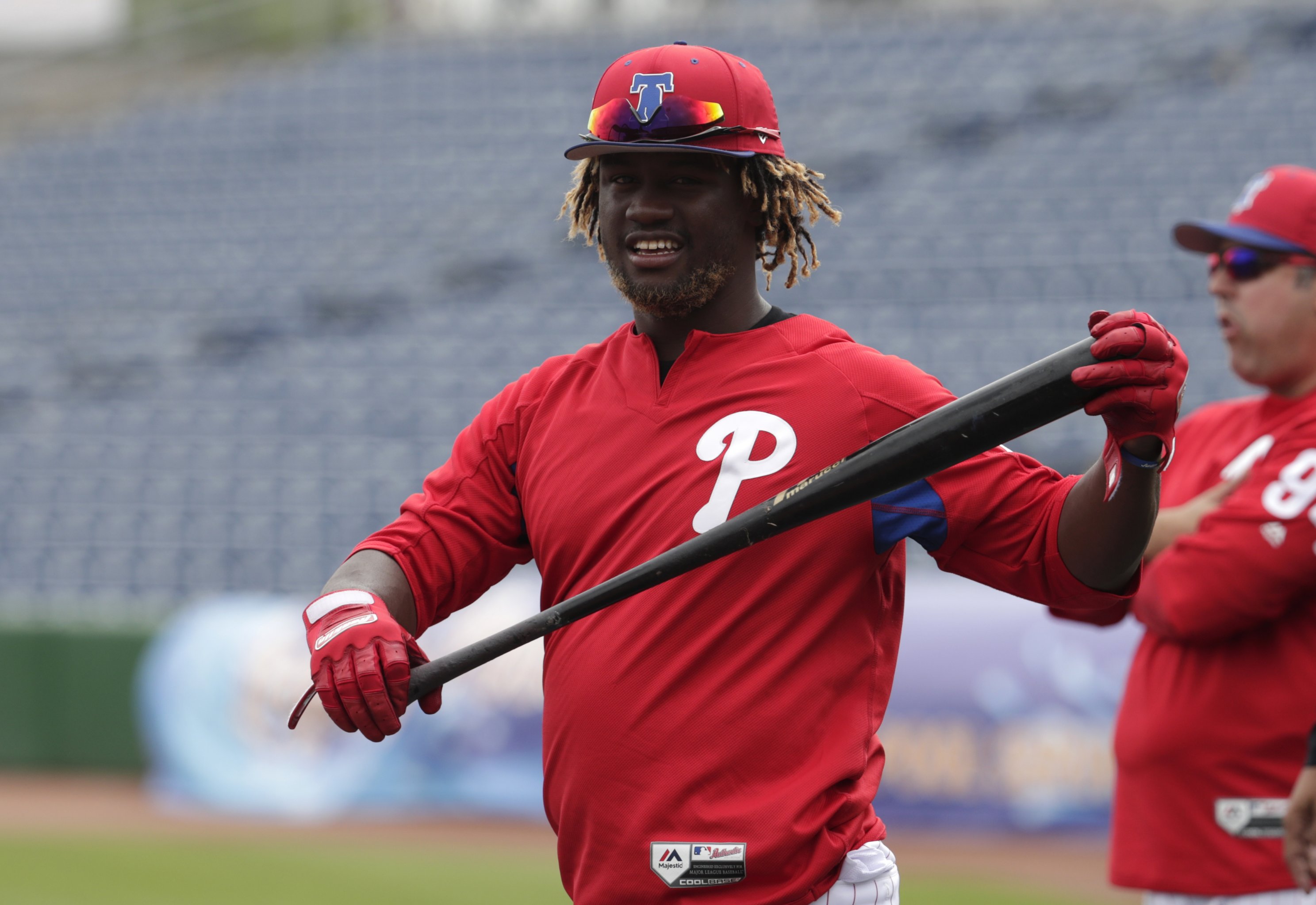 Philadelphia Phillies - Brandon Marsh looking excited, while holding the  end of a baseball bat in his right hand. He is wearing batting gloves, a  long sleeve red shirt, a red hat