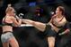 Cris Cyborg (right) kicks Holly Holm.